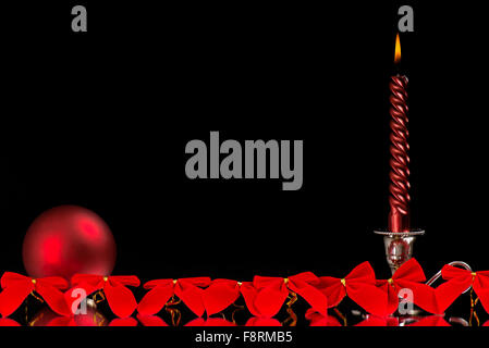 one red spiral candles in silver candlesticks, glass red ball in front of many red greasy black background as a Christmas decora Stock Photo