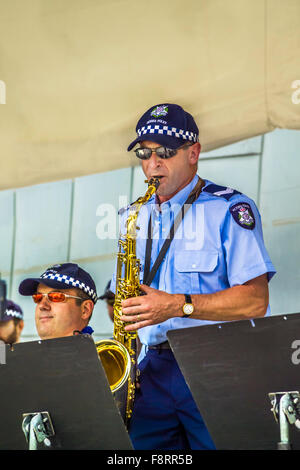 Uniformed male police officer saxophonist performing live with his colleagues at Federation Square, Melbourne Australia Stock Photo