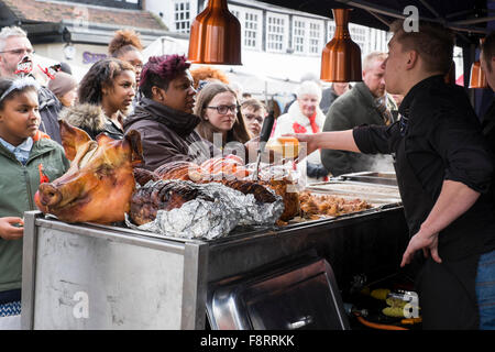 A pigs head on a stall as customers queue for hot pork rolls at Bridgnorth Christmas market, Shropshire, England, UK Stock Photo