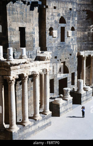 A female tourist photographs the 2nd century Roman theater, in Bosra, Syria. Constructed probably under Trajan, it is the only monument of this type with its upper gallery in the form of a covered portico which has been integrally preserved. It was fortified between 481 and 1231. Stock Photo