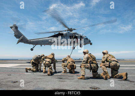 Sailors assigned to Explosive Ordnance Disposal Mobile Unit (EODMU) 3, Platoon 3-1-1 and Chilean navy sailors brace themselves after fast-roping out of an MH-60S Seahawk helicopter, assigned to the 'Black Knights' of Helicopter Sea Combat Squadron
