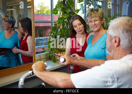 Elderly man in gym talking to two women Stock Photo