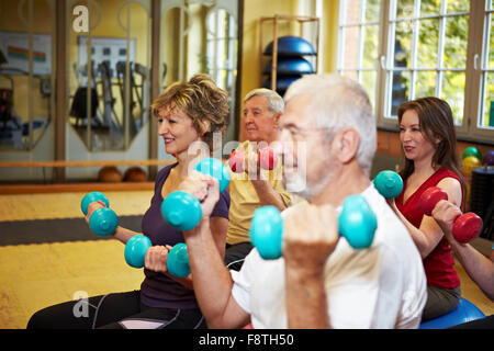Mixed group doing dumbbell exercises in a gym Stock Photo