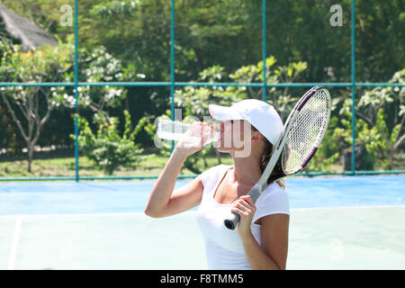 Female tennis player on court drinking water Stock Photo