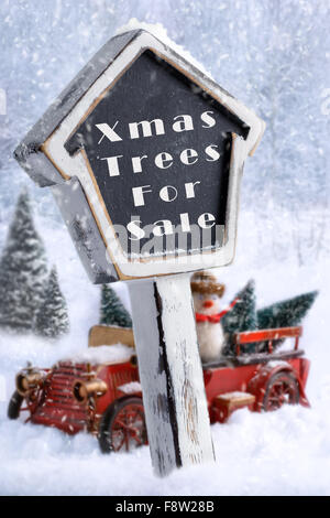 Christmas trees for sale sign with vintage red truck carrying trees in background Stock Photo