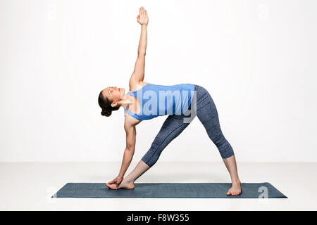 Woman practices yoga asana utthita trikonasana Stock Photo