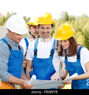 Team of happy smiling workers look at construction blueprint Stock Photo
