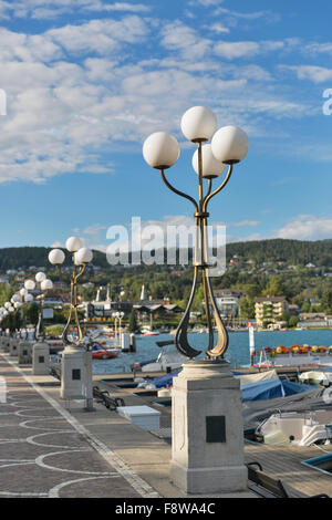 street lights along the Lake Worthersee waterfront with moored boats in Velden village, Austria Stock Photo