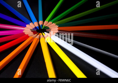 Brightly colored pencil crayons from the red side of the colour spectrum are arranged into a circle or wheel making a burst Stock Photo