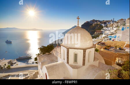 Thira (capital city of Santorini) - greek white church overlooking the sea and sun on blue sky, Santorini Island, Greece Stock Photo