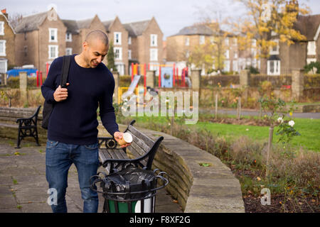 man throwing rubbish in the bin in a park Stock Photo