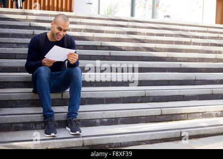 young man sitting on steps reading a letter Stock Photo