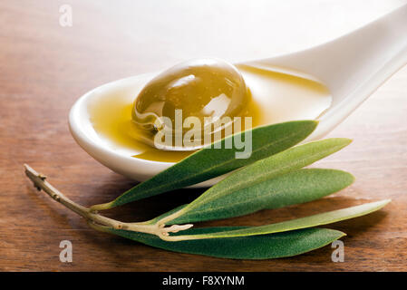 Virgin olive oil and olive fruit on white spoon close up. Stock Photo