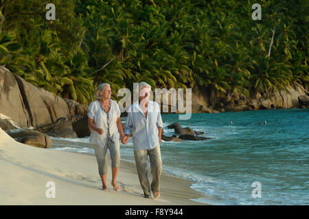 Elderly couple walking along  seashore Stock Photo