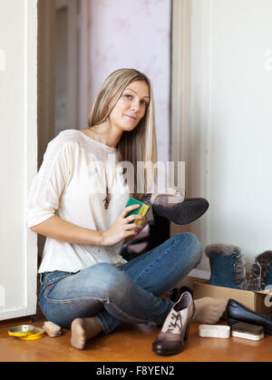 Woman sits on floor and cleans shoes Stock Photo