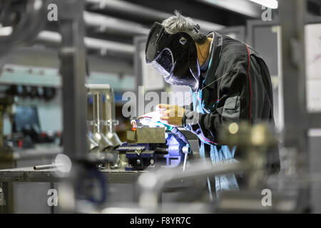 Industrial worker welding in metal factory. Stock Photo