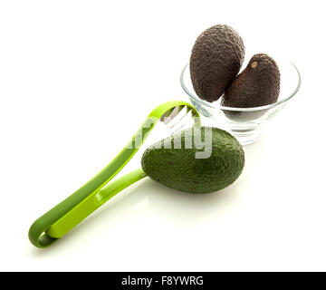 Avocados in glass bowl with slicer isolated on white background Stock Photo