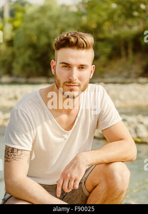 Portrait of handsome young man in white t-shirt outdoors, looking in camera Stock Photo