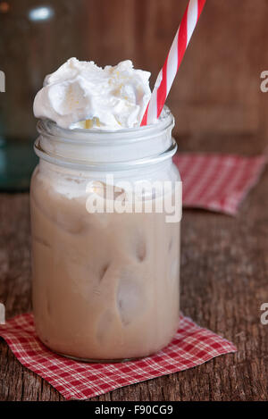 Iced coffee in an old style mason jar with red and white straw and whipped topping. Stock Photo