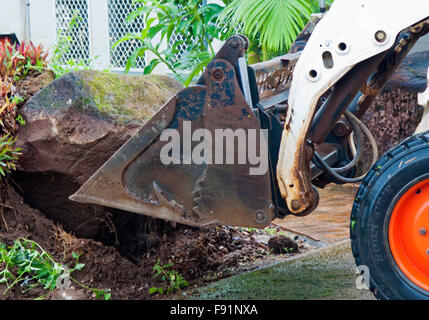 a bobcat moving a large garden stone Stock Photo