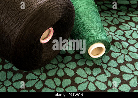 Textile Still Life - Close Up of Large Spools of Brown and Green Thread on Floral Patterned Background with Copy Space Stock Photo