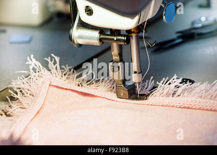 Close Up of Sewing Machine Needle Affixing Fringe Edging on Pink Garment Stock Photo