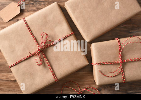High angle view of three plain brown paper wrapped Christmas Presents on a rustic wood table. Stock Photo