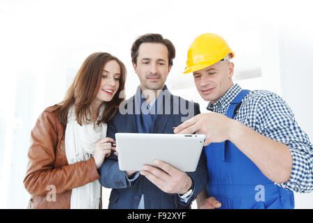 Worker and couple using tablet pc at construction site Stock Photo