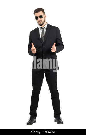 Secret agent with sunglasses aiming hand gun gesture at camera. Full body length portrait isolated over white studio background Stock Photo