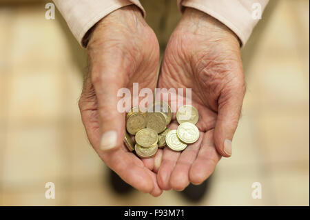 Shiny gold pound coins held out in hands showing all small savings and money plea for help poverty stricken pensioner Stock Photo