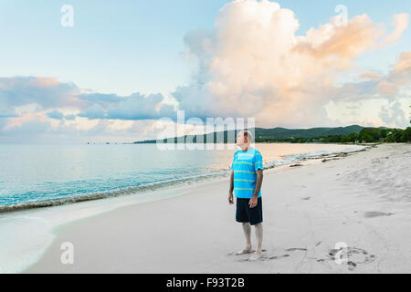 A 77 year old Caucasian man standing on the beach at sunrise on St. Croix, U.S. Virgin Islands. Stock Photo