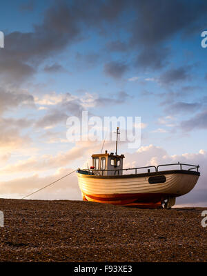 A lone fishing boat catches the last light at Dungeness, Kent. Stock Photo