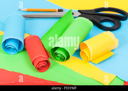 still life - scissor, pencil and rolled color paper on sheets of torn paper Stock Photo