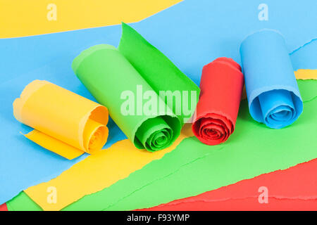 still life - rolled color paper on sheets of torn paper Stock Photo