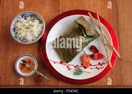 Roasted Salmon in Banana Leaves, spicy dill and lime paste, coconut rice, Vietnamese dipping sauce, peppers, Stock Photo