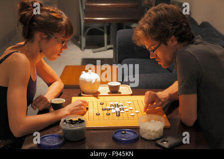 Young couple playing go, strategic board game Stock Photo