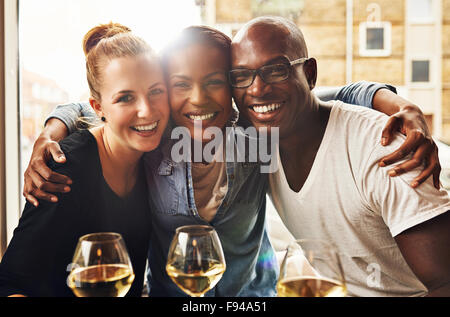 Three ethnic best friends smiling at camera and hugging Stock Photo