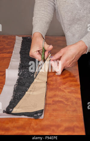 dressmaker at work cutting piece of black and grey cloth Stock Photo