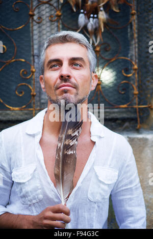 Sexi Man in a white shirt and ornamental window on background. And Dream Catcher. Stock Photo