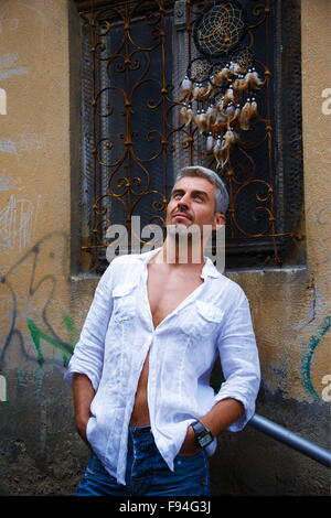 Sexi Man in a white shirt and ornamental window on background. And Dream Catcher. Stock Photo