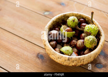 close up of chestnuts in basket on wooden table Stock Photo