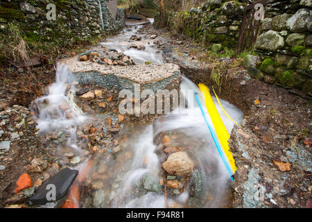 A culvert overflowing on Blue Hill, Ambleside in the Lake District on Saturday 5th December 2015, during torrential rain from storm Desmond. It has washed away a track revealing the gas pipe underneath. Stock Photo