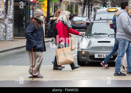 London, UK. 13th Dec, 2015. A man wearing an anti pollution mask crosses the road with shoppers at a pedestrian crossing in Oxford Street whilst the traffic waits at red lights. Anti pollution pressure groups have urged London's next mayor to pedestrianise Oxford Street as they warn the air quality will reach “breaking point” during the annual Christmas shopping rush. Credit:  London pix/Alamy Live News Stock Photo