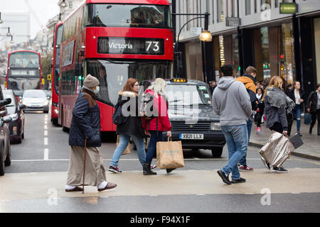 London, UK. 13th Dec, 2015. A man wearing an anti pollution mask crosses the road with shoppers at a pedestrian crossing in Oxford Street whilst the traffic waits at red lights. Anti pollution pressure groups have urged London's next mayor to pedestrianise Oxford Street as they warn the air quality will reach “breaking point” during the annual Christmas shopping rush. Credit:  London pix/Alamy Live News Stock Photo