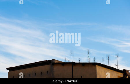 Group of old terrestrial tv antennas on roof with blue sky background Stock Photo