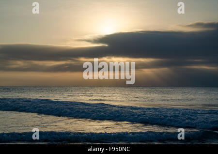 Sun peaking over clouds as it rises over the Pacific Ocean on the New South Wales mid north-coast of Australia Stock Photo