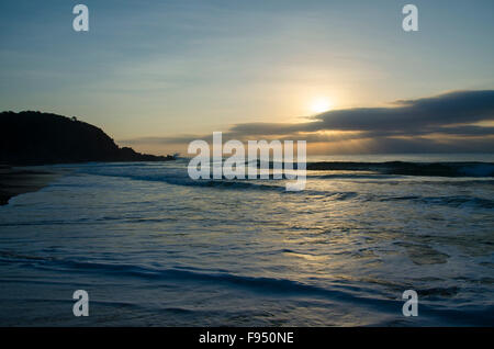 Sun peaking over clouds as it rises over the Pacific Ocean on the New South Wales mid north-coast of Australia Stock Photo