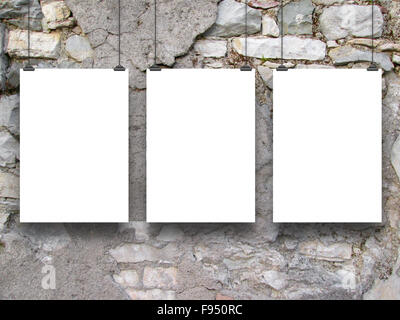 Three hanged paper sheet frames with clips on grey damaged brick wall background Stock Photo