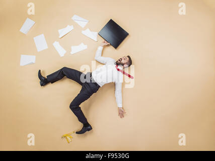 Handsome manager having an accident. Studio shot on a beige background. Funny pose. Stock Photo