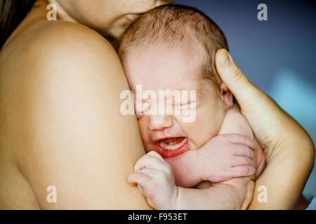 Newborn baby crying in mother hands indoor Stock Photo